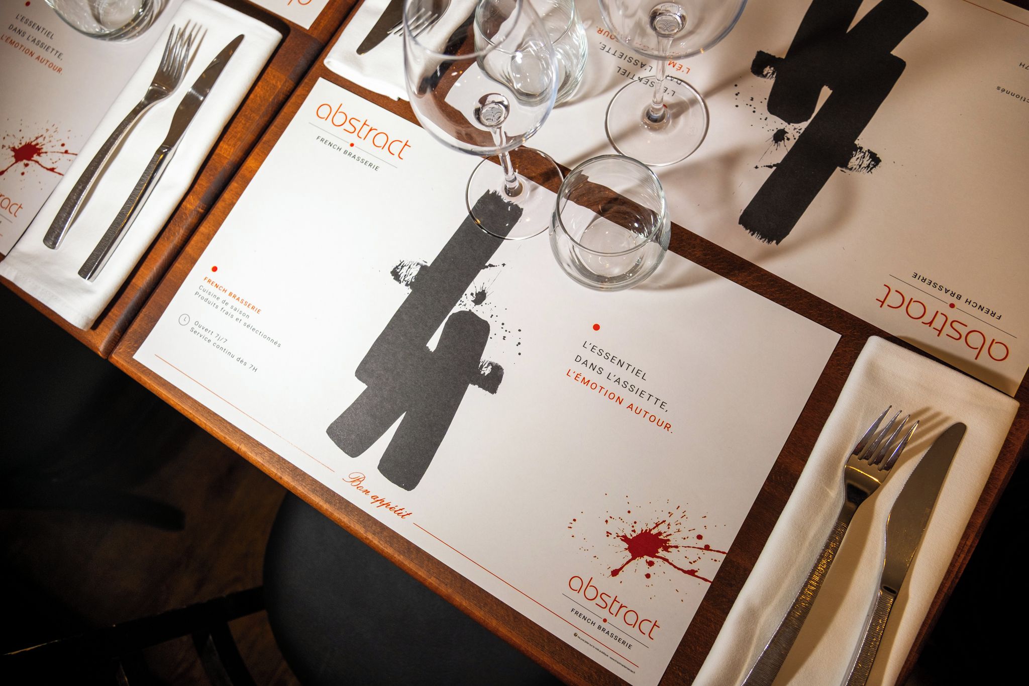 A table set with a menu, wine glasses, and cutlery.