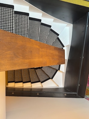 Eine Wendeltreppe mit Holzgeländer und schwarz-weiß gemusterten Stufen.