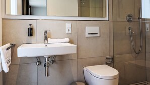 A modern bathroom with a white sink, a toilet, and a glass shower enclosure. - Munich Finest Apartments Studio 11 by Interhome (Munich)