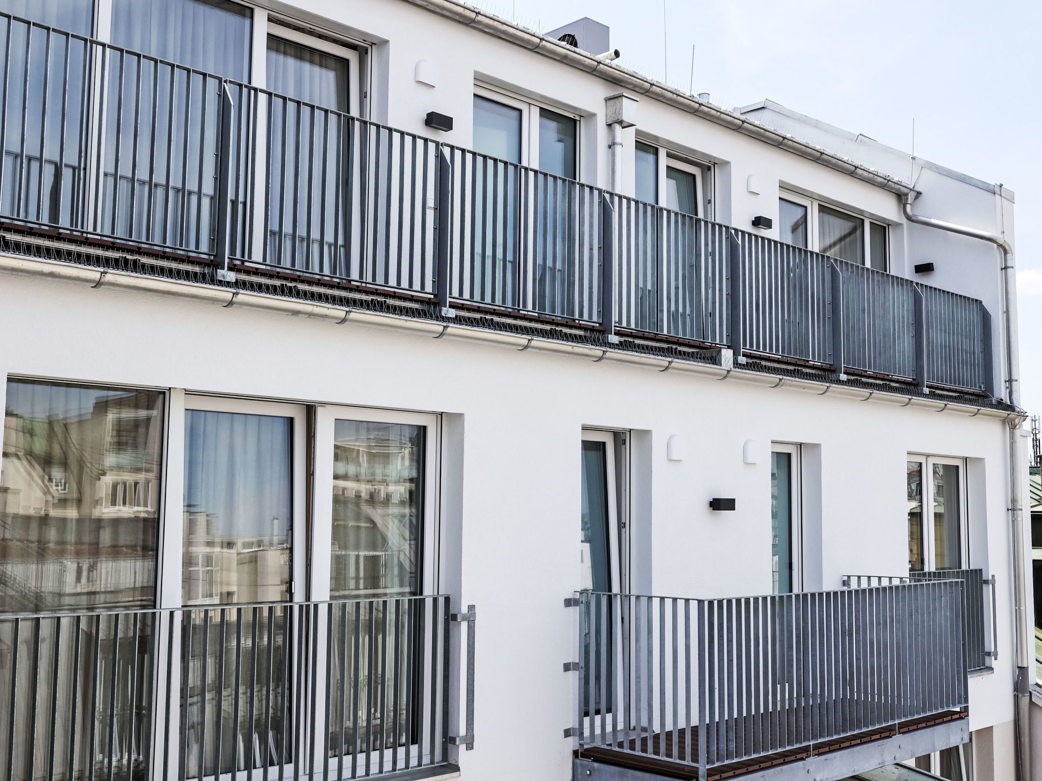 Un edificio moderno de dos pisos con balcones, ventanas amplias y una fachada limpia.
