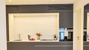 Eine moderne Küche mit Marmorfliesenspiegel, integriertem Spülbecken und einer Edelstahl-Dunstabzugshaube.