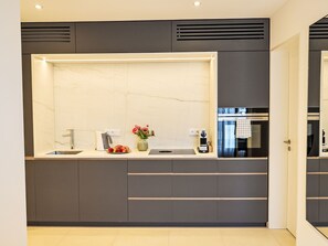 Eine moderne Küche mit Marmorfliesenspiegel, integriertem Spülbecken und einer Edelstahl-Dunstabzugshaube.