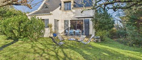 A house with a stone facade, a sloped roof, and a patio with outdoor furniture.