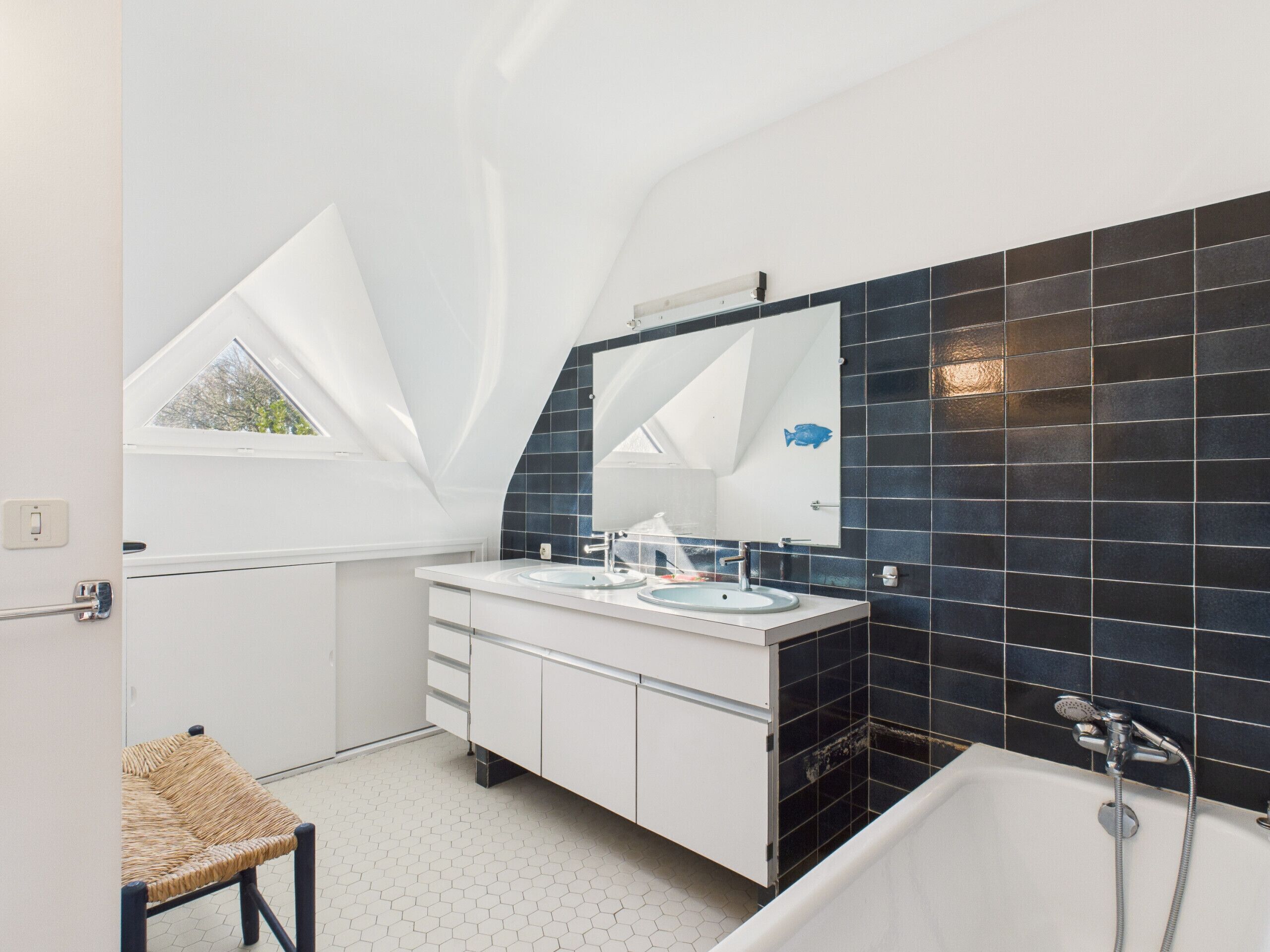 A modern bathroom with a skylight, a bathtub, and a vanity with a mirror.
