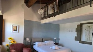 A bedroom with a bed, a chair, a nightstand, a lamp, and a wall with artwork. - Old Style Apartment in Florence in Residence with shared pool (Tavarnuzze)