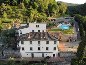 A white building with a tiled roof, a swimming pool, and a garden area with lounge chairs. - Old Style Apartment in Florence in Residence with shared pool (Tavarnuzze)