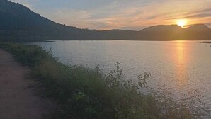 Ein Sonnenuntergang über einem stillen See mit einem Pfad am Ufer.