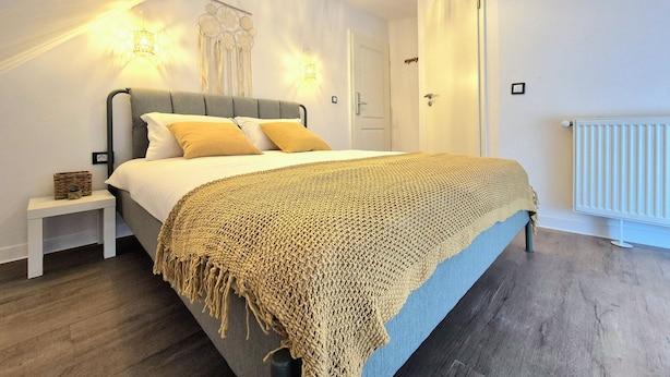 Ein Schlafzimmer mit Bett, Nachttisch, Wandleuchte und Heizkörper.