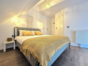 Ein Schlafzimmer mit Bett, Nachttisch, Wandleuchte und Heizkörper.