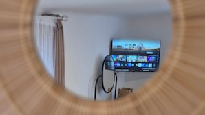 Ein an der Wand befestigter Fernseher zeigt eine Streaming-Dienstoberfläche mit mehreren Symbolen.