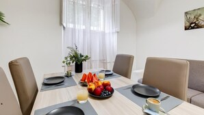 Un comedor con una mesa dispuesta para dos personas, que incluye un frutero, vasos de jugo y una taza de café.