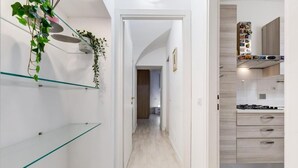 Una cocina moderna con armarios de madera clara, una estufa a gas y una repisa de vidrio con plantas.