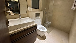 Et moderne badeværelse med vask, toilet og glasafskærmet brusebad.