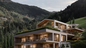 Ett modernt hus i två våningar med ett platt tak, stora fönster och en balkong med utemöbler.