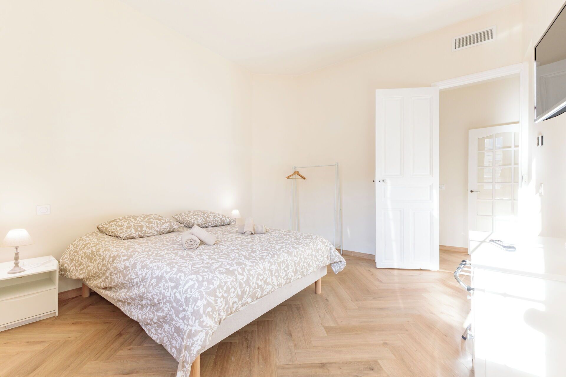 A bedroom with a bed, bedside table, lamp, and a wardrobe.