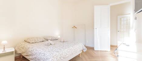 A bedroom with a bed, bedside table, lamp, and a wardrobe.