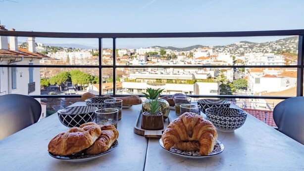 A table with croissants and bowls on a balcony overlooking a cityscape. - Apartment in Cannes with 1 bedrooms sleeps 4 (Cannes)