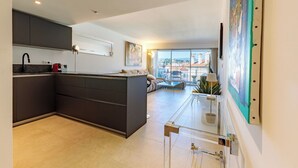Une cuisine moderne avec des meubles de couleur sombre, un îlot central intégré et une table à manger avec un plateau en verre.