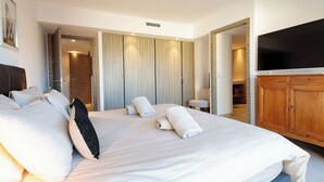 Une chambre d’hôtel dotée d’un grand lit, d’un téléviseur à écran plat, de meubles en bois et d’un dressing.