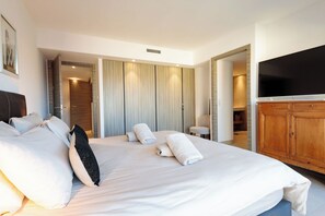 Ein Hotelzimmer mit einem großen Bett, einem Flachbildfernseher, Holzmöbeln und einem begehbaren Kleiderschrank.