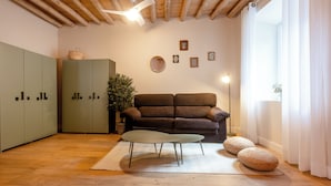 Una habitación con techo de madera, un sofá marrón, un armario verde y un espejo redondo en la pared.