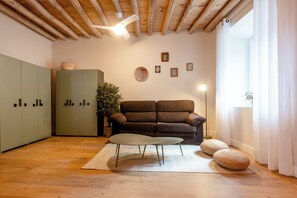 Una habitación con techo de madera, un sofá marrón, un armario verde y un espejo redondo en la pared.