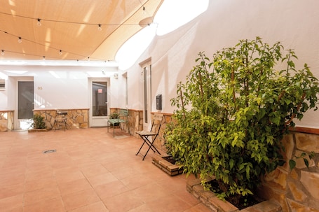A spacious indoor area with a stone wall, a wooden ceiling, and a potted plant.. Hospedería Boho Granada by eme hoteles