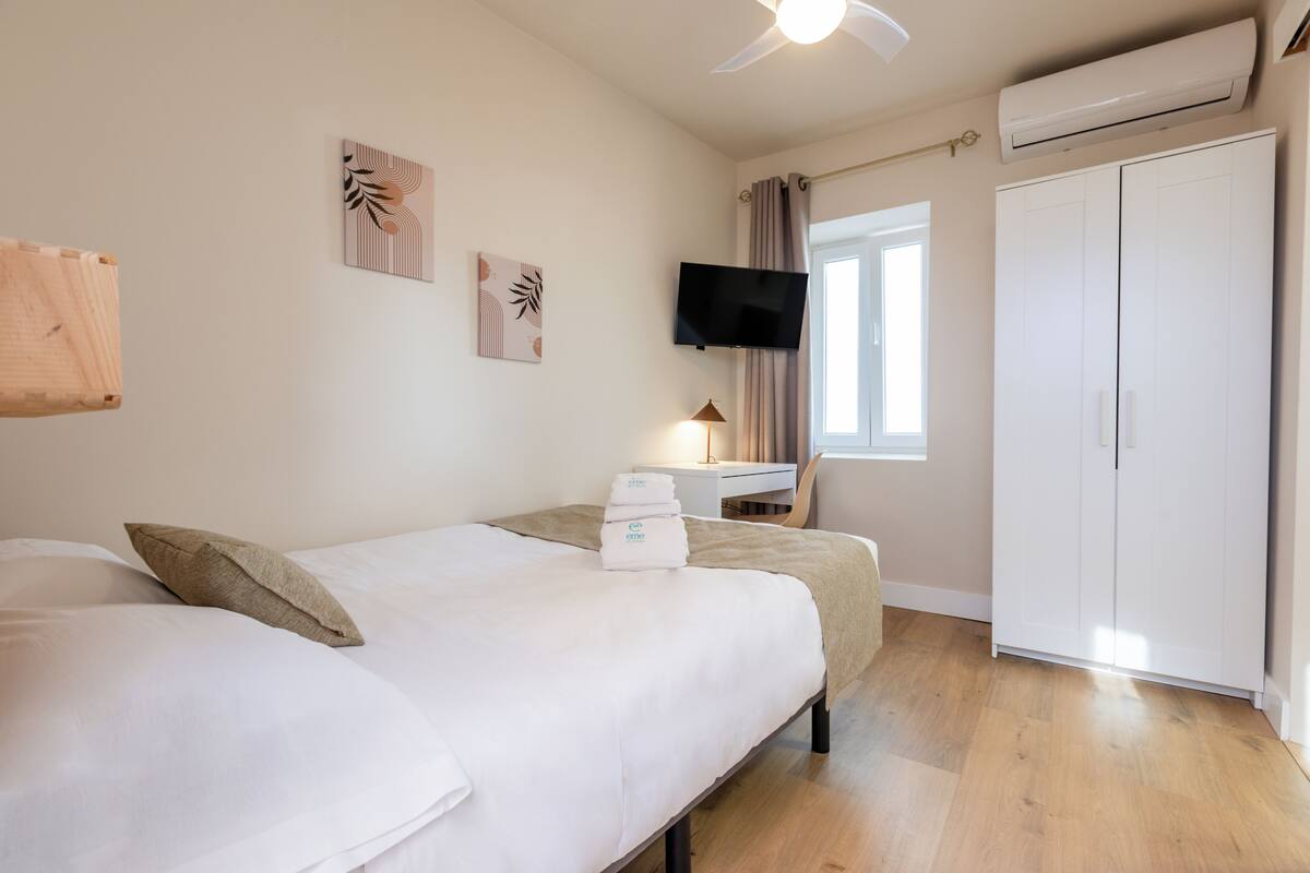 Ein Hotelzimmer mit Bett, Schreibtisch, Fernseher und Kleiderschrank.