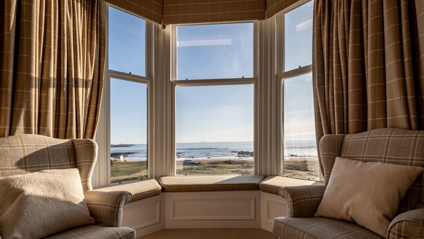 A corner bay window with a view of the ocean.