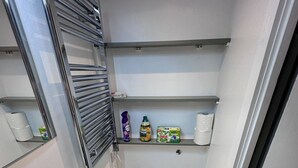Een kleine badkamer met toilet, wastafel en planken boven het toilet.