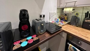 Een keuken met een koffiezetapparaat, een broodrooster en een bak koffiepads.