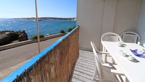 Un balcone con vista sul mare, un tavolo con sedie e una ventola.