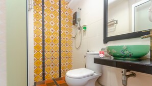 A bathroom with a toilet, a shower, a green decorative bowl on the sink, and a mirror above the sink. - Capital O 91277 Nur Villa Hotel (Malacca City)