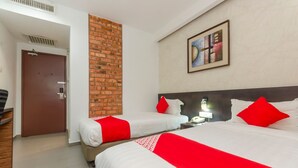 A hotel room with two beds, a brick accent wall, a painting, and a door. - Capital O 91277 Nur Villa Hotel (Malacca City)