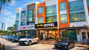 A hotel with a modern facade, multiple parking spaces, and a visible sign for an academic institution. - Capital O 91277 Nur Villa Hotel (Malacca City)