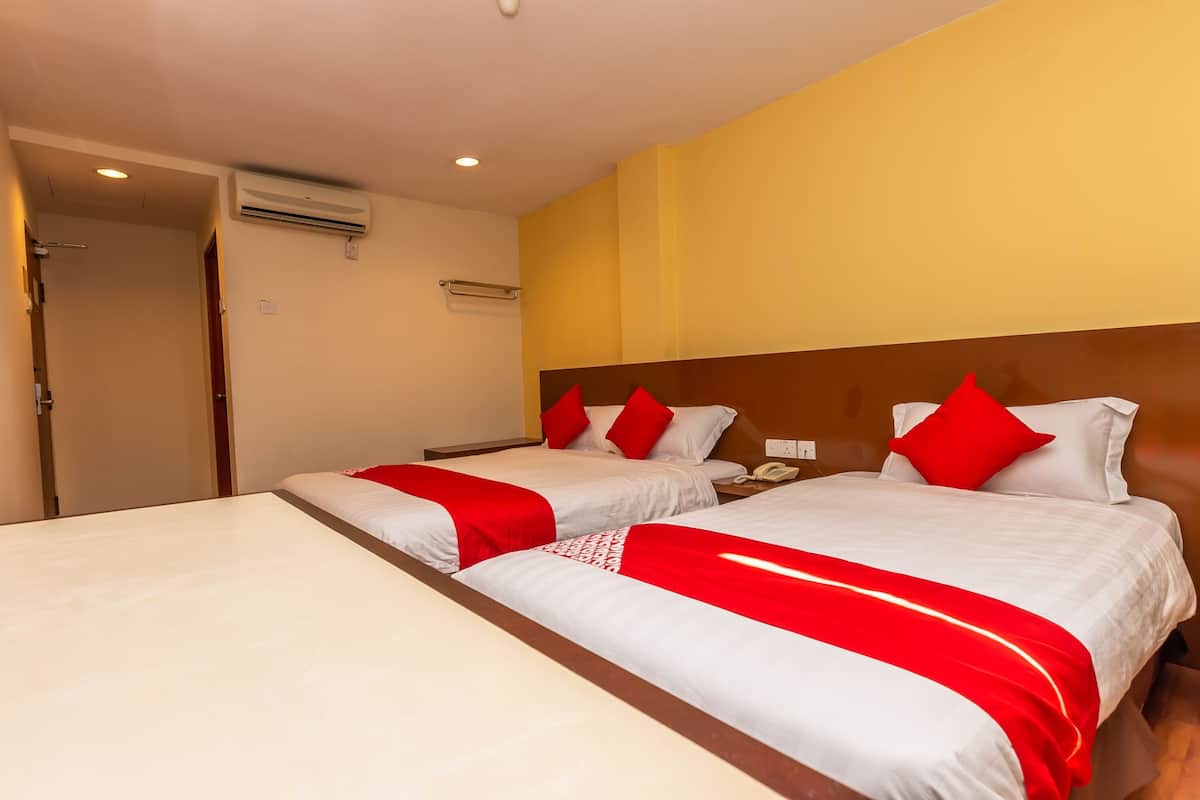 Une chambre d’hôtel avec deux lits, une tête de lit en bois, une table de chevet et un appareil de climatisation.