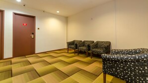 A room with patterned carpet, a door with a red sign, and four patterned chairs. - Capital O 91277 Nur Villa Hotel (Malacca City)