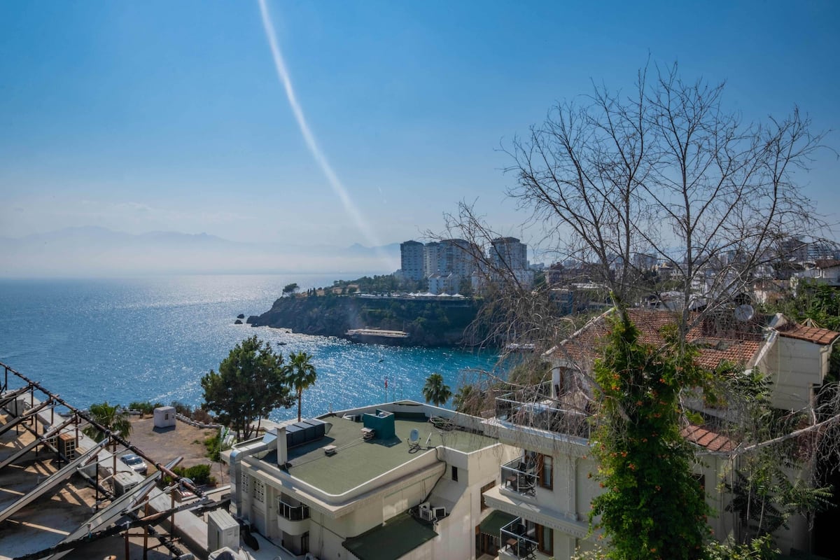 A coastal cityscape with a view of the sea, buildings, and a clear sky.
