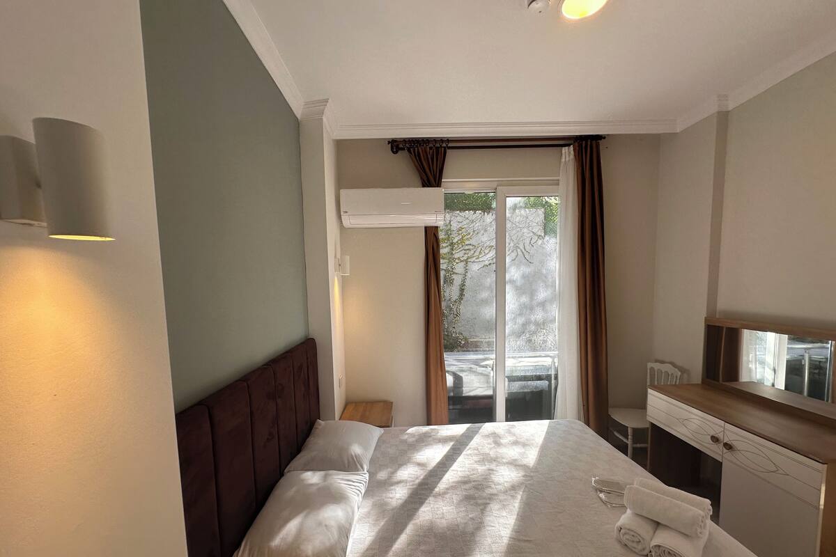 A hotel room with a bed, a desk, a chair, and a window with curtains.
