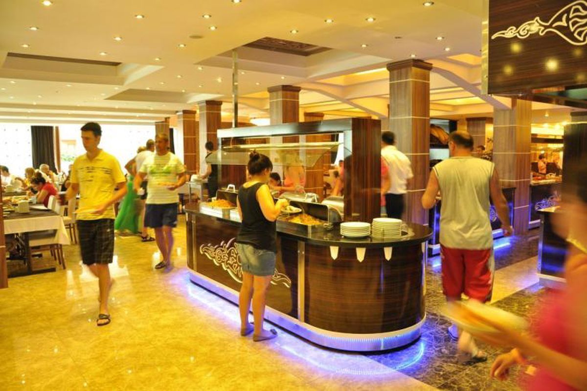 A buffet area with a counter and food display, surrounded by people.