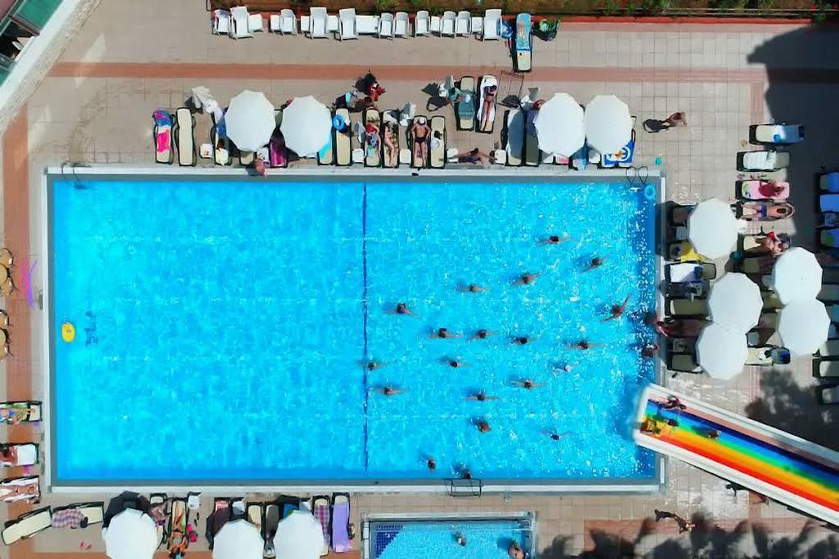 A large swimming pool with multiple lanes, surrounded by lounge chairs and umbrellas.