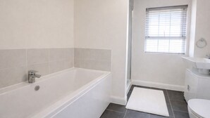 Une salle de bain moderne avec une baignoire, des toilettes et une fenêtre.