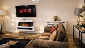 Un salon doté d’une cheminée, d’un téléviseur fixé au-dessus et d’un canapé agrémenté de coussins décoratifs.