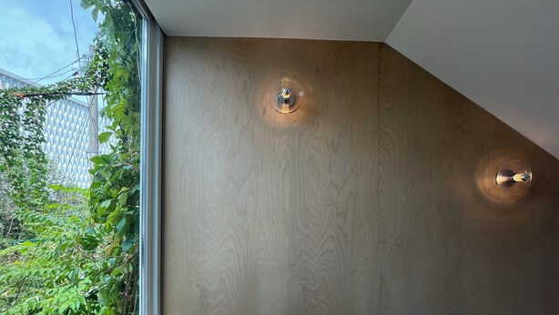 A corner of a room with a wooden wall, a window, and a light fixture. - BOTANIK HOTEL (Cheonan)