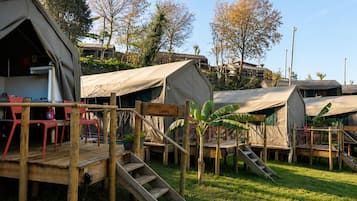 En campingplads med flere telte, en træterrasse og et skilt med teksten 'CAMPAS'.