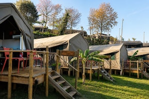 Un terrain de camping avec plusieurs tentes, une terrasse en bois et un panneau indiquant « CAMPAS ».