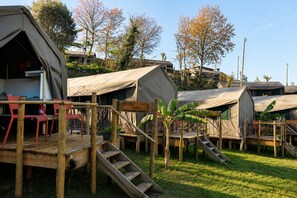 Un terrain de camping avec plusieurs tentes, une terrasse en bois et un panneau indiquant « CAMPAS ».