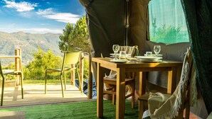 A tent with a dining table set for two, chairs, and a view of mountains. - Safari Glamping Portugal Koi Fish (Ventosa)