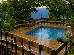 Un pontile in legno che circonda una piscina rettangolare con vista su un paesaggio montuoso.