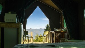 A tented accommodation with a bed, a table with chairs, and a view of mountains. - Safari Glamping Portugal Koi Fish (Ventosa)